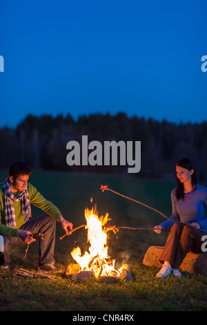 Young couple cook by campfire romantic night countryside Stock Photo