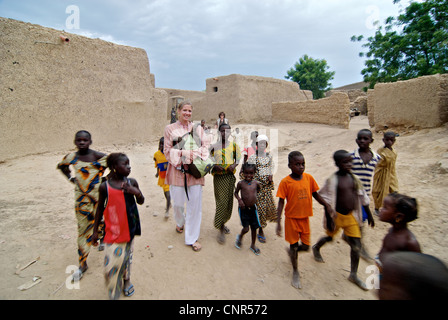 A tourist walking with the local children in Mopti, Mali. Stock Photo