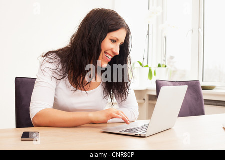 Portrait of a cheerful woman chatting online using a laptop Stock Photo