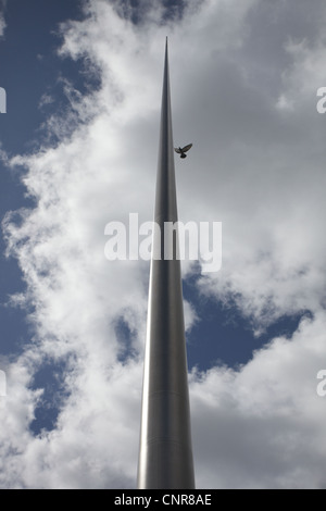 A bird flying close to the Monument of Light or Spire of Dublin which is located on O'Connel Street in the city centre. Stock Photo