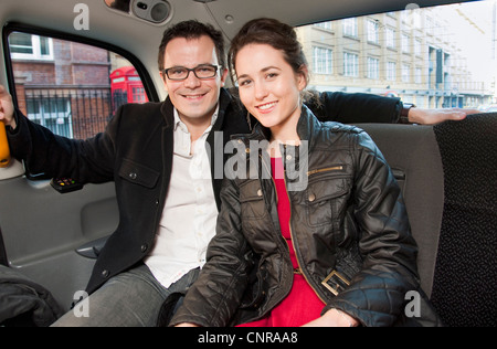 Couple smiling in back seat of car Stock Photo