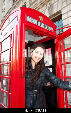 Woman smiling in red telephone booth Stock Photo