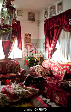 The old lady of Awarta, who sleeps only with her photos of martyrs., the old lady in her bed, in the middle of the rom. Stock Photo