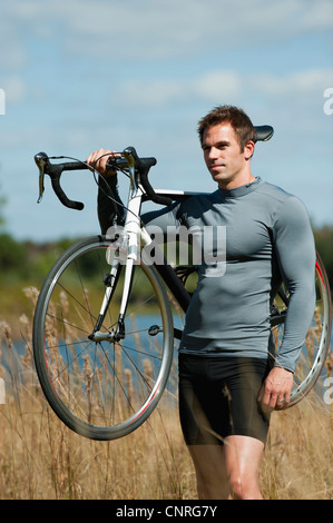 Man carrying bicycle on shoulder in nature, portrait Stock Photo