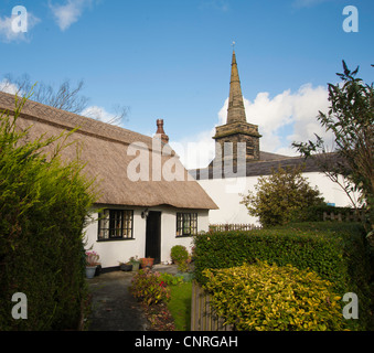 Traditional English village with thatched cottage and church Stock Photo