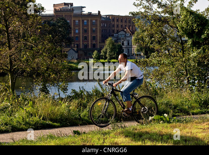 cyclist at Ruhr river in Hattingen with Birschel mill in background, Germany, North Rhine-Westphalia, Ruhr Area, Hattingen Stock Photo
