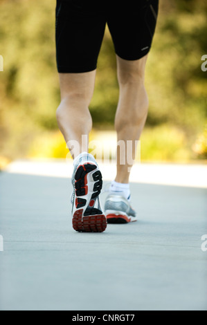 Back view of man with muscular legs riding black bike on fresh air ...