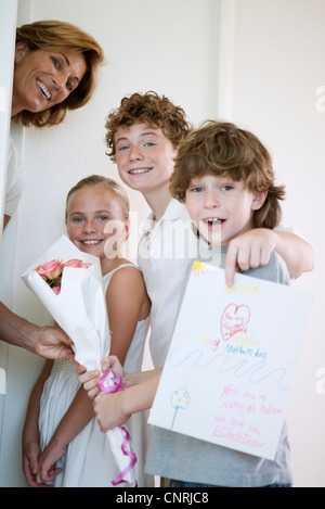 Children giving mother flowers and hand-made greeting card Stock Photo