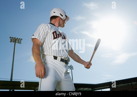 Baseball player holding bat, looking over shoulder Stock Photo