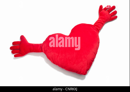 A red heart shaped cushion with outstretched hands Stock Photo