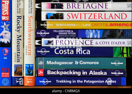 Collection showing assortment of travel guides and guidebooks about worldwide holiday destinations on a bookcase bookshelf Stock Photo