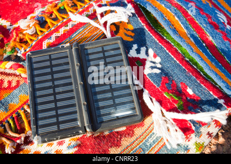 Berber Moroccan woven cloth rugs and bags in the Anti Atlas mountains of Morocco, North Africa, with a solar charger. Stock Photo