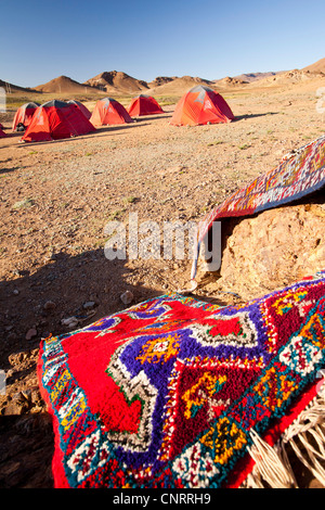 Berber Moroccan woven cloth rugs and bags in the Anti Atlas mountains of Morocco, North Africa, with a trekking camp site Stock Photo