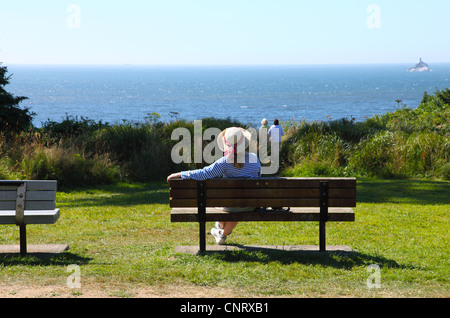 Woman on a bench looking out at the Pacific ocean view. Stock Photo