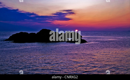 The blood-red April sun sets in the ocean west of Kirkehamn on the island of Hidra in south-western Norway, Norway Stock Photo