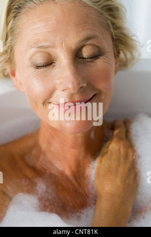 Mature woman relaxing in bubble bath with eyes closed, portrait Stock Photo