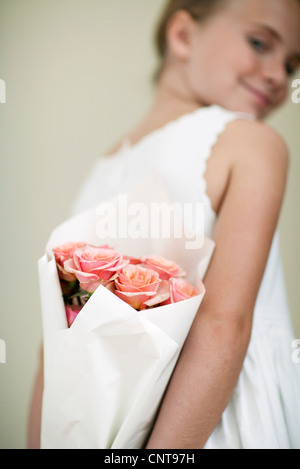 Girl holding bouquet of roses behind back
