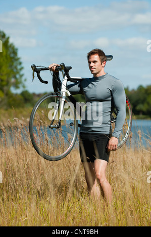 Man carrying bicycle on shoulder in nature, portrait Stock Photo