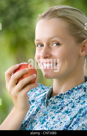 Smiling young woman holding apple, portrait Stock Photo