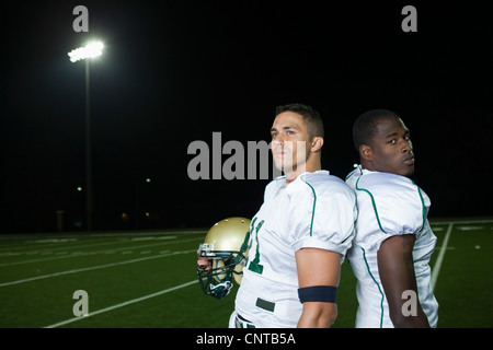 Football players standing back to back on field Stock Photo