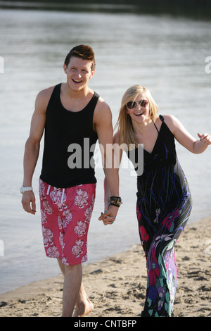 Young couple walking holding hands on a Scottish beach. Stock Photo