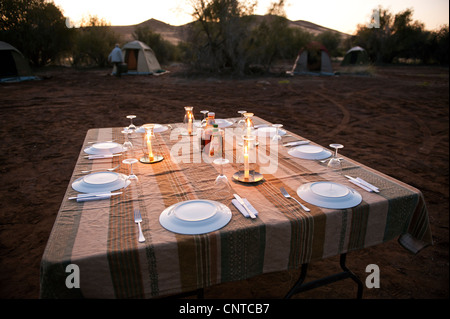 Dining in the wild wilderness NAMIBIA desert Damaraland evening light table lay layed candles romantic romance camp camping nigh Stock Photo