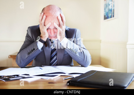 Businessman reading notes at desk Stock Photo