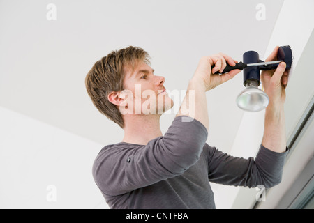 Man installing light fixture in house Stock Photo