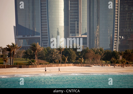 runners at the beach in front of the newly built, modern Skyscrapers Etihad Towers in Abu Dhabi, United Arab Emirates, Asia Stock Photo