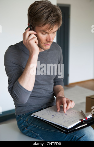 Man on cell phone taking notes Stock Photo