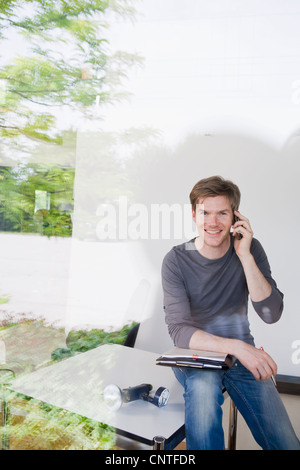 Man on cell phone taking notes Stock Photo