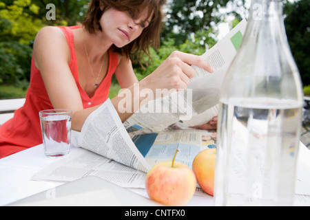 Woman reading newspaper in backyard Stock Photo