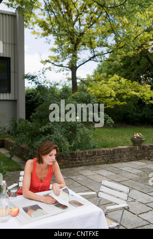 Woman reading newspaper in backyard Stock Photo