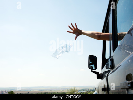 Woman throwing bottle out car window Stock Photo