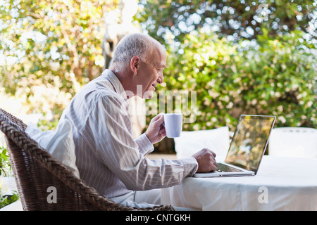 Older man using laptop outdoors Stock Photo
