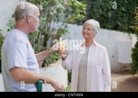 Older couple drinking juice in backyard Stock Photo