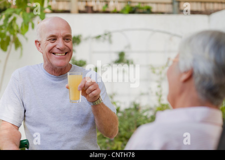 Older couple drinking juice in backyard Stock Photo