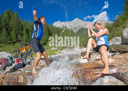 man and woman with mountain bikes on a tour in the alpine mountains, having fun at a mountain creek, Austria, Upper Austria, Gmunden Stock Photo