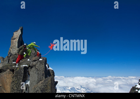two ski alpinists climbing in the mountains, throwing the rope, France, Alps Stock Photo