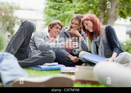 Students using cell phone on grass Stock Photo