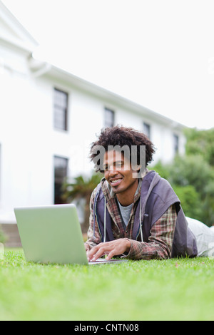 Student using laptop on grass on campus Stock Photo