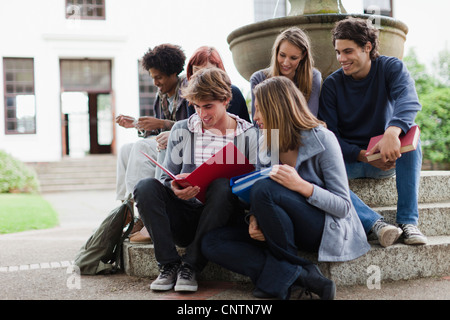 Students reading on fountain on campus Stock Photo