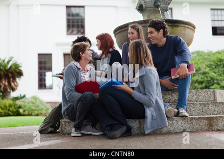 Students talking on fountain on campus Stock Photo