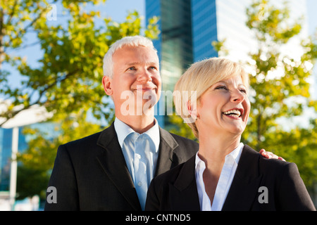 Business people - mature or senior - standing in a park outdoors in front of a office building Stock Photo