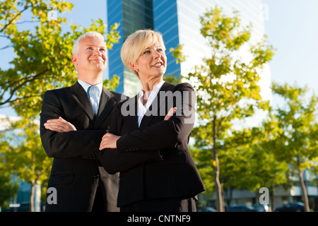 Business people - mature or senior - standing in a park outdoors in front of a office building Stock Photo