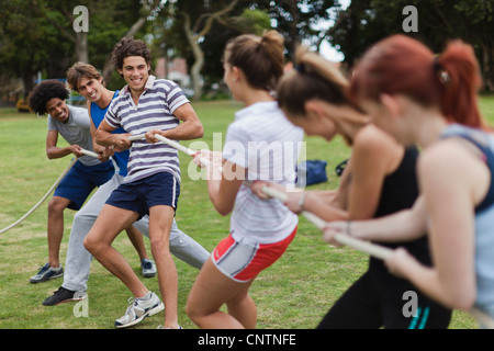 Friends playing tug of war in park Stock Photo