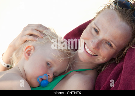 Smiling woman cuddling baby on beach