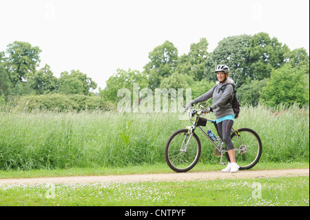 Older woman riding bicycle on rural road Stock Photo