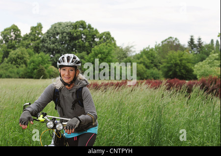 Older woman riding bicycle on rural road Stock Photo