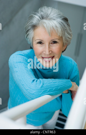 Smiling older woman climbing stairs Stock Photo